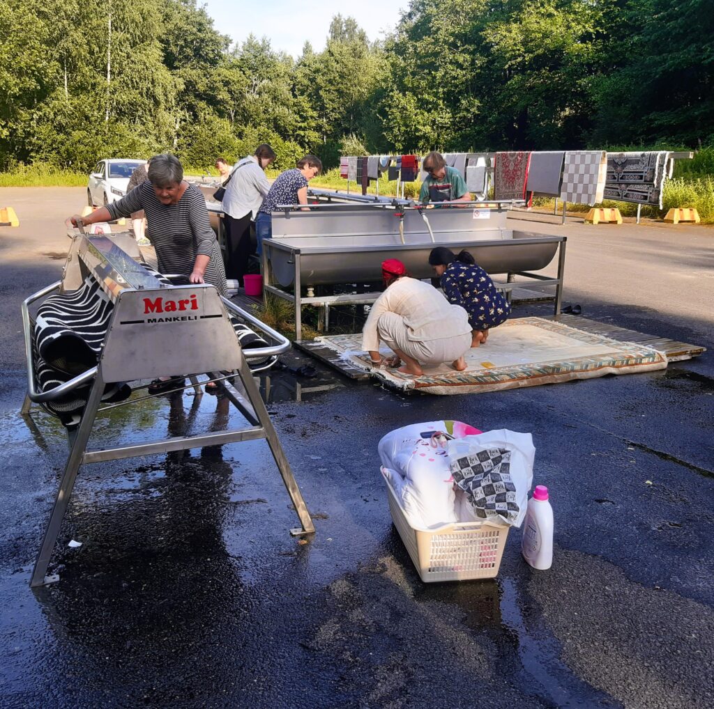 Vrouw achter wringer op openbare wasplaats in Finland